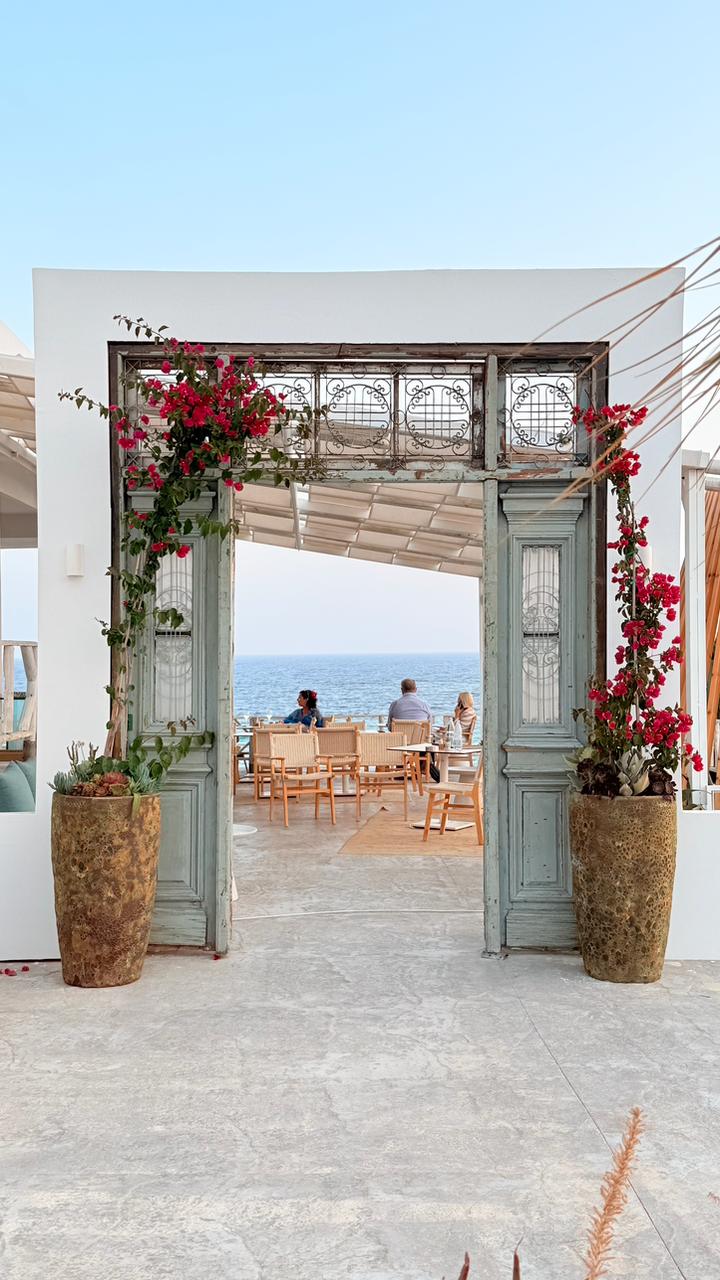 Puerta antigua con buganvilla que abre a una terraza frente al mar