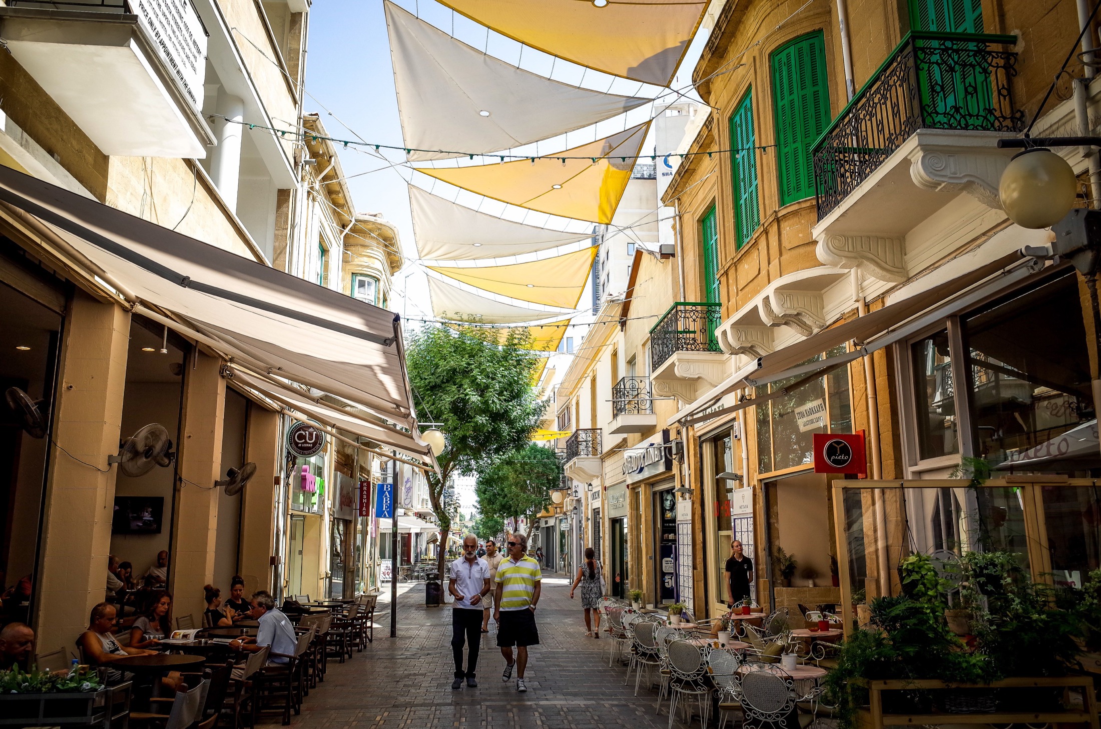 Calle peatonal del casco antiguo de Nicosia con terrazas y toldos amarillos