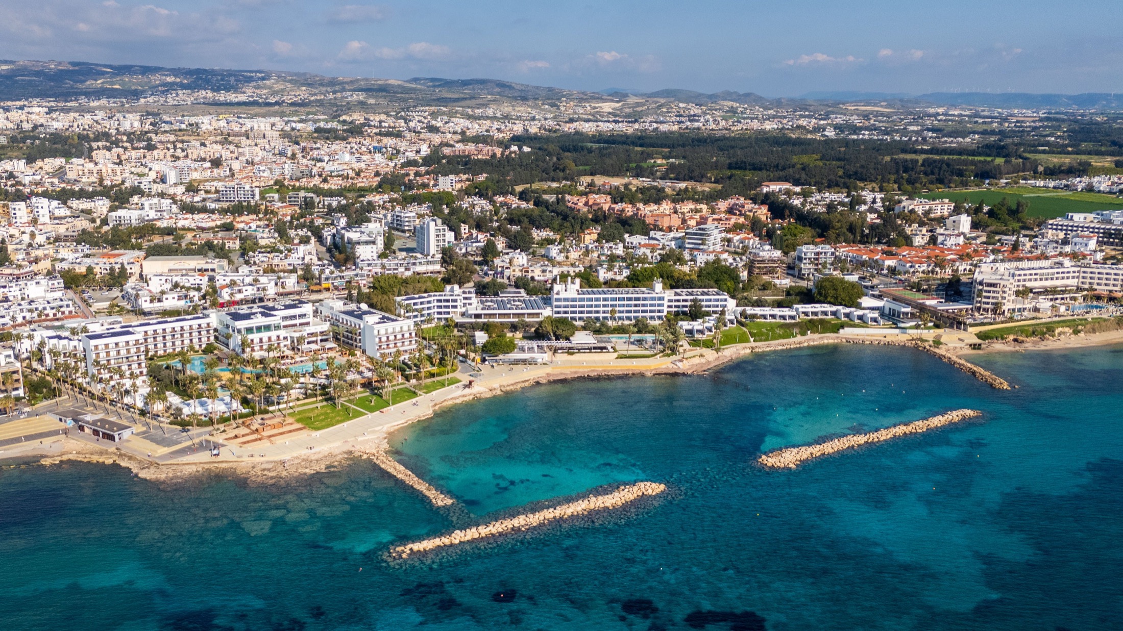 Vista aérea de la costa de Pafos con hoteles, paseo marítimo y aguas turquesas