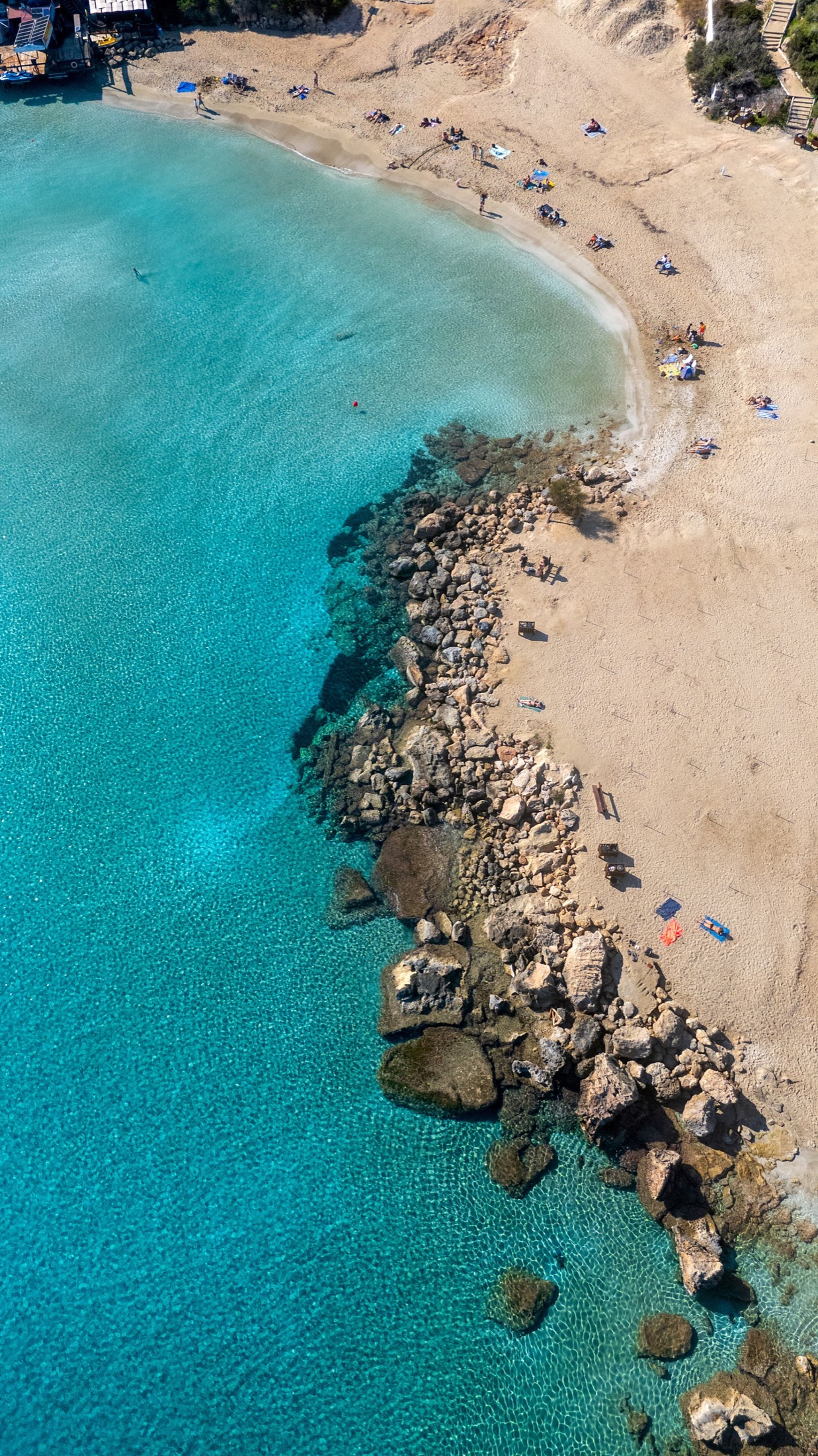 Vista aérea de una playa de Protaras con agua turquesa y rocas junto a la arena